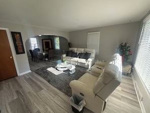 A living room with a sofa, coffee table, and a dining area with chairs and a table.
