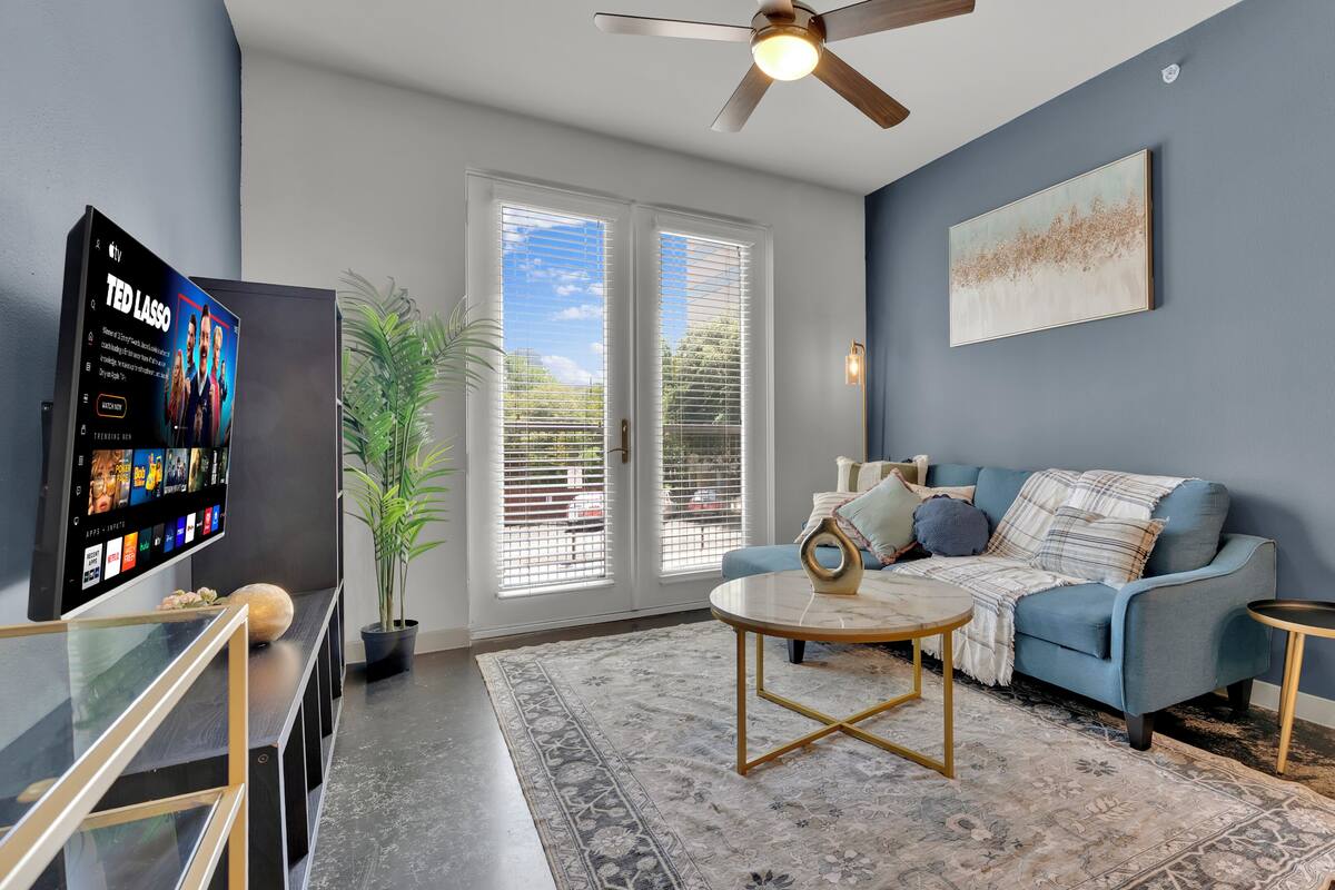 A living room with a TV, sofa, coffee table, and a potted plant.