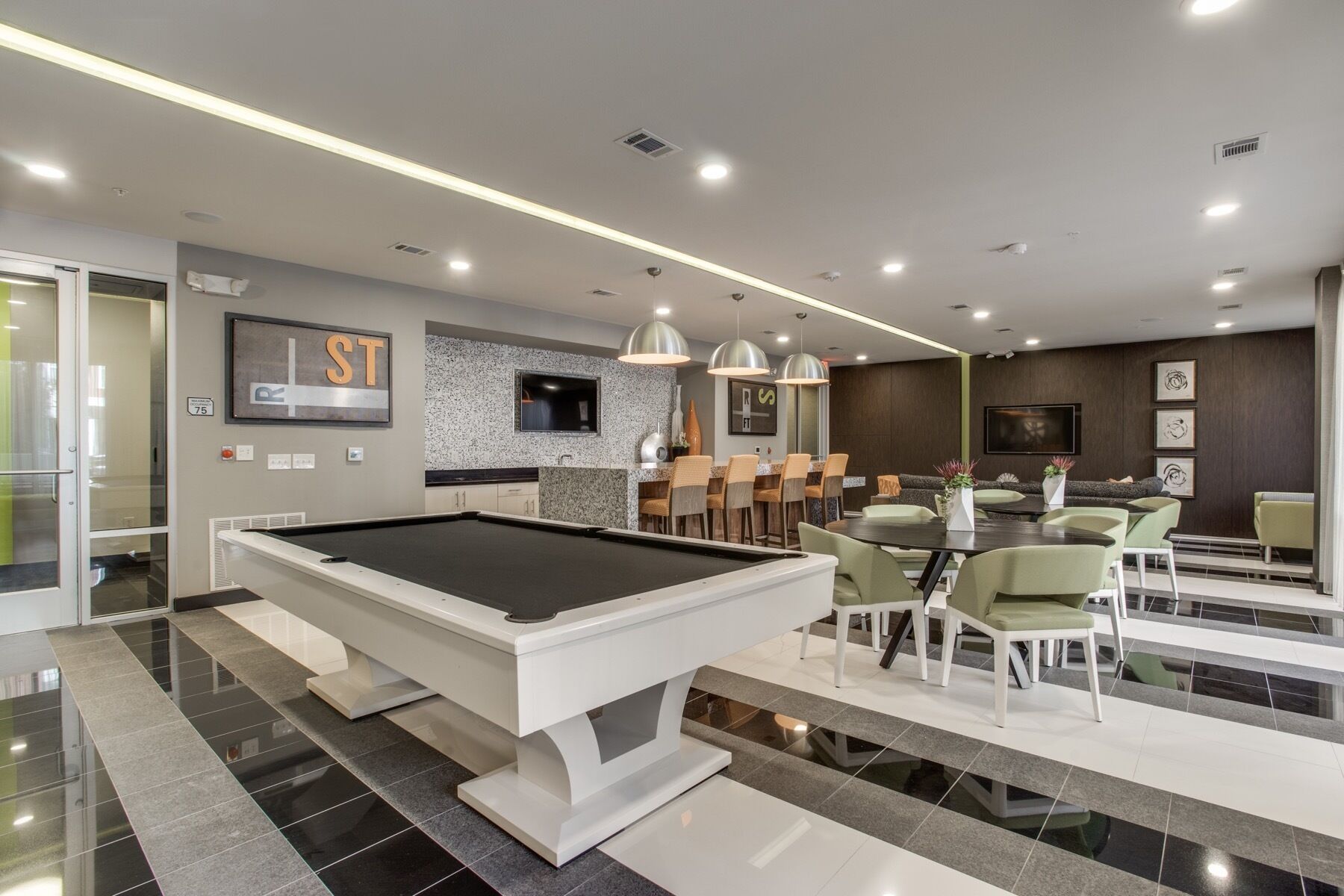 Een moderne binnenzwembadruimte met een pooltafel, een bar en een eethoek.