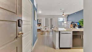 A modern kitchen with a central island, a dining area with a table and chairs, and a built-in dishwasher. - Apartmint at Bell Katy Trail Dallas (Dallas)