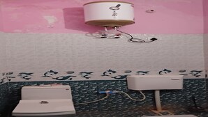 Un baño con pared rosa, inodoro blanco, lavamanos blanco y zona de ducha.