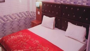 Un dormitorio con una cama, una mesita de noche y una pared con azulejos decorados.