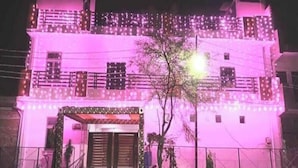Un edificio de varios pisos con balcones, una entrada porticada y un árbol en frente.