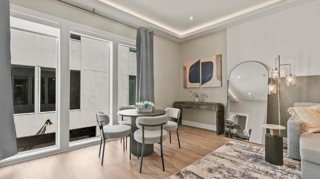 A modern living room with a round dining table, two chairs, a sofa, a coffee table, and a floor lamp.