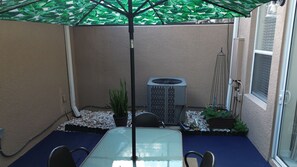 Une terrasse avec une table, des chaises, un parasol et un radiateur.