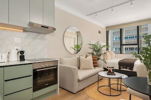Eine moderne Küche mit Backofen von Bosch, einer Couch, einem runden Spiegel und Blick auf ein Gebäude durch große Fenster.
