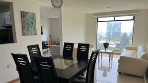 A modern living room with a dining area, a sofa, and a view of the city. - La Paz Department (Heroica Puebla de Zaragoza)