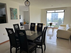 Ein modernes Wohnzimmer mit Essbereich, einer Couch und Blick auf die Stadt.