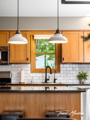 Una cocina moderna con armarios de madera, un grifo negro y luces colgantes.