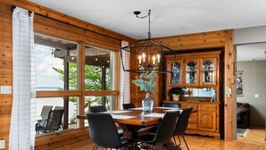 Een houten interieur met een eettafel, stoelen en een kroonluchter.