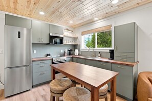 A modern kitchen with grey cabinets, stainless steel appliances, and a wooden table.