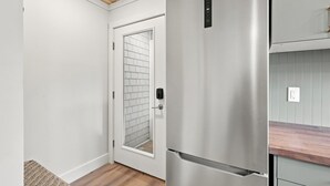 Eine moderne Küche mit einem Edelstahlkühlschrank, einer Holz Arbeitsplatte und einer weißen Küchenrückwand.