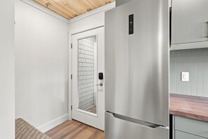 A modern kitchen with a stainless steel refrigerator, a wooden countertop, and a white tiled backsplash. - Crystal Lake East End Retreat with Dock, Hot Tub & Sunset Views (Beulah)
