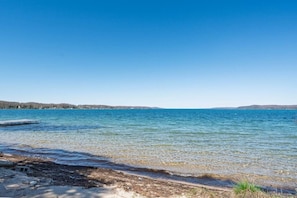 Ein klarer See mit einem Steg, ruhigem Wasser und einer entfernten Uferlinie.