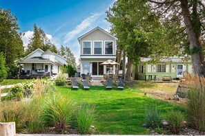A two-story house with a patio area and outdoor seating. - Crystal Lake East End Retreat with Dock, Hot Tub & Sunset Views (Beulah)