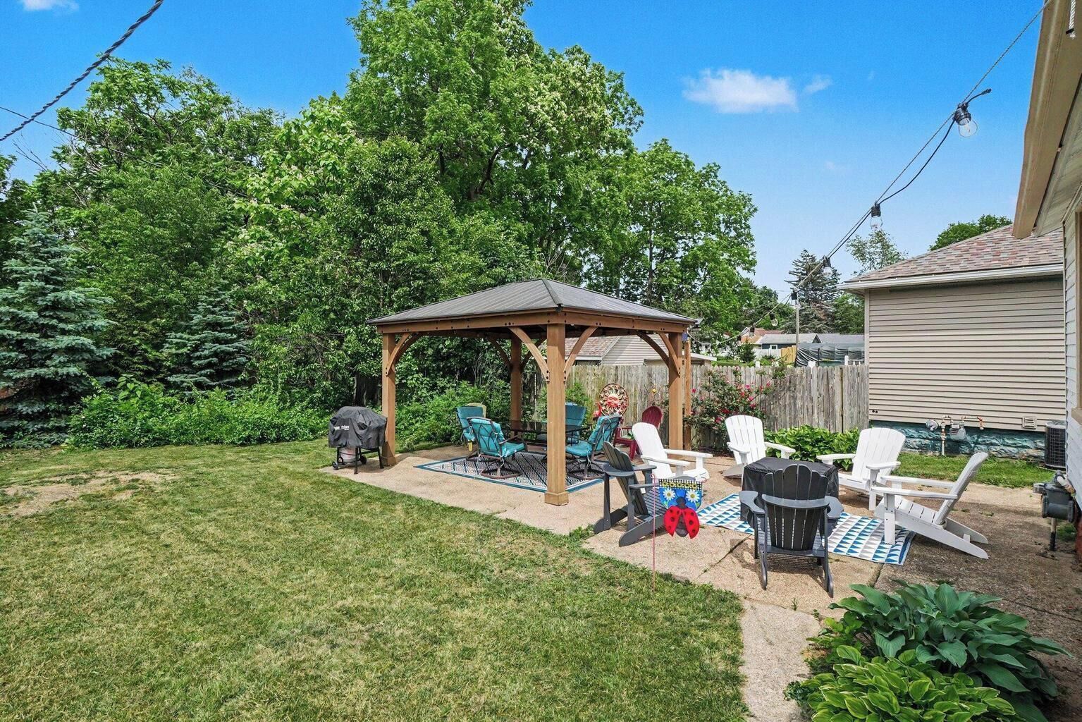Un jardin avec un patio couvert, un espace salon extérieur et un barbecue.