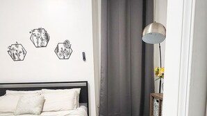 Ein Schlafzimmer mit einem Bett, einem Nachttisch mit Lampe, einer Wand mit sechseckartigen Verzierungen und einem grauen Vorhang.