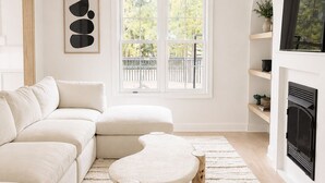A modern living room with a sectional sofa, a round coffee table, and a fireplace.