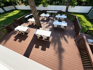 A deck with multiple tables and chairs, surrounded by a white fence and trees. - Lovely Abode — Architectural Warmth, Intentionally Designed (Freehold)