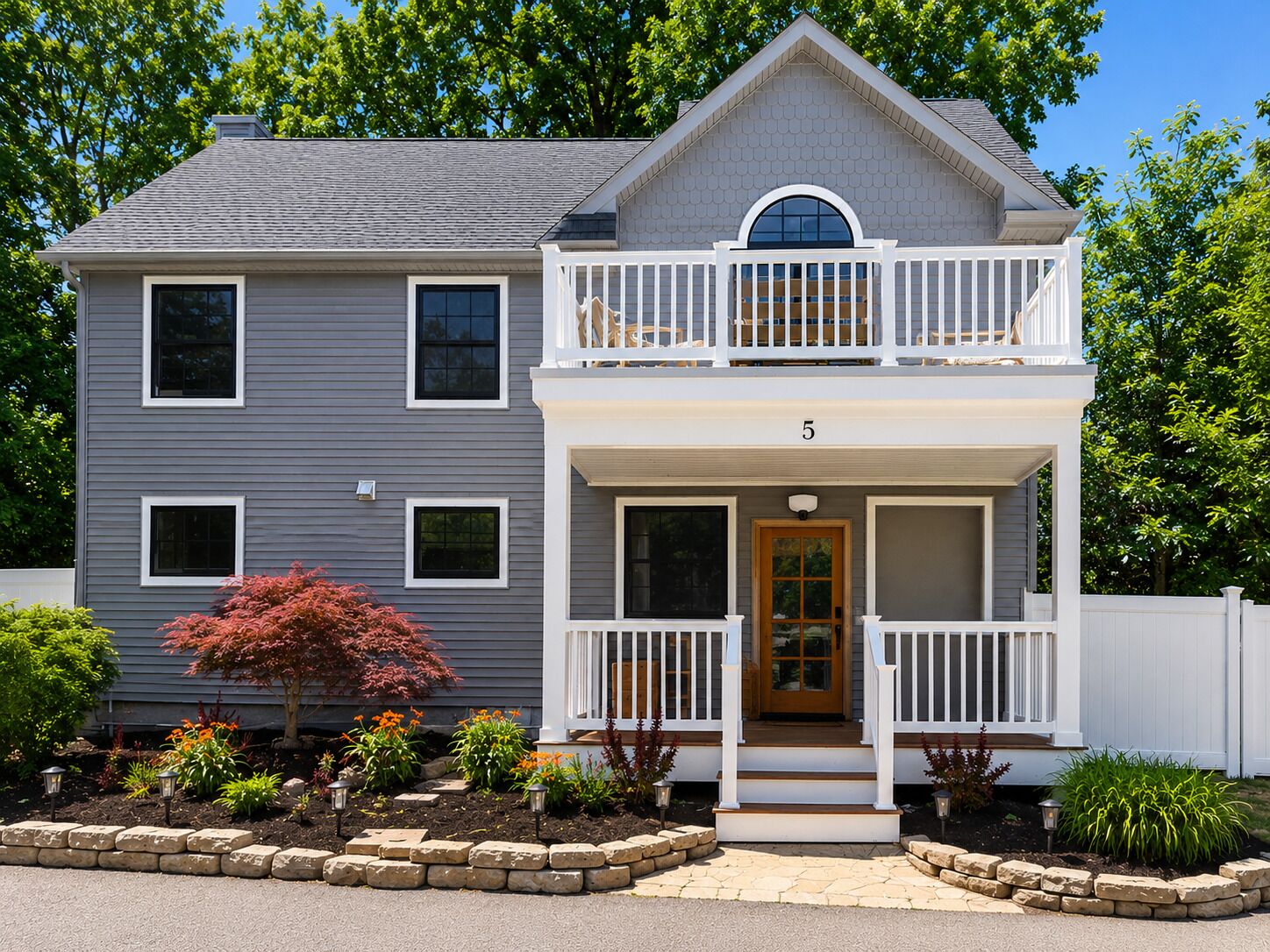 A two-story house with a front porch, a balcony, and a number '5' on the front door.