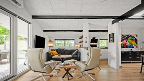 En moderne stue med en sofa, to lænestole, et sofabord og et fjernsyn.