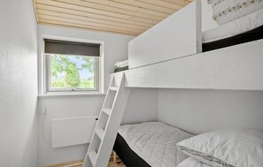 Ein Schlafraum mit Etagenbetten, einem Fenster und einer weißen Wand.