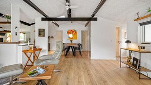 En rummelig opholdsstue med spisebord, stole, sofa og TV-møbel.
