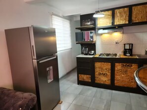 Eine Küche mit Kühlschrank, Kaffeemaschine und Holzschränken.