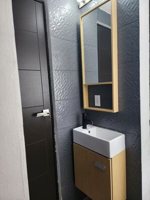 Ein Badezimmer mit Waschbecken, Holzschrank, Spiegel und Tür.