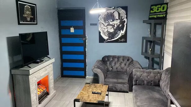 A living room with a fireplace, a sofa, a television, and a door with blue panels. - Apartment in El Chopo (Ciudad de México)