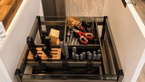 A kitchen drawer with utensils, a cutting board, and a wooden spoon. - The Ember Suite l Designer Guest House (Kissimmee)
