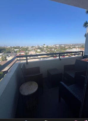 A balcony with a view of a residential area, a round table, and two chairs. - Top-Floor Studio. Pool, Hot Tub &FreeParking (Los Angeles)
