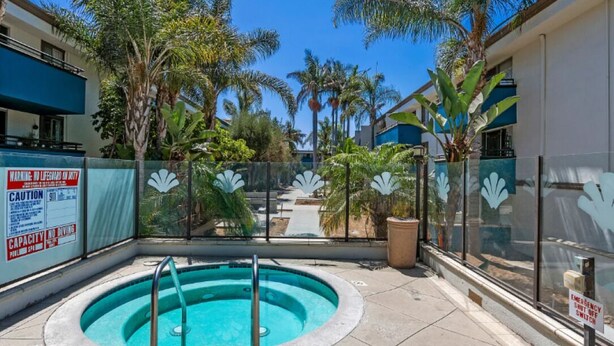 Una piscina sul tetto con barriera in vetro, palme e cielo azzurro limpido.