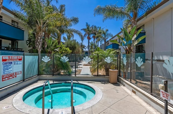 A rooftop pool with a glass barrier, palm trees, and a clear blue sky. - Top-Floor Studio. Pool, Hot Tub &FreeParking (Los Angeles)