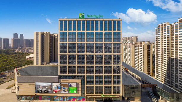 Um hotel Holiday Inn com fachada de vidro moderna, rodeado por edifícios altos.
