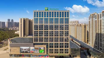 A Holiday Inn hotel with a modern glass facade, surrounded by high-rise buildings.