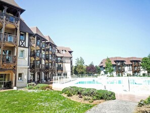 A multi-story hotel with balconies, a swimming pool, and a well-maintained lawn. - Résidence du golf by Interhome (Deauville-Trouville)