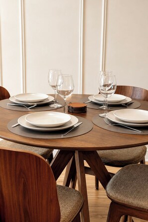 A round dining table with four chairs, each with a brown cushion, set with white plates, cutlery, and wine glasses. - Résidence du golf by Interhome (Deauville-Trouville)