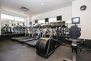 Ein Fitnessraum mit mehreren Laufbändern, Crosstrainern und einem stationären Fahrrad.