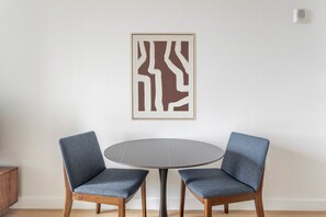 A room with a round table and two chairs with wooden legs and fabric upholstery. - Blueground | Financial District, rooftop pool, nr Brooklyn Bridge (New York)