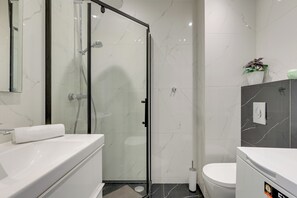 A modern bathroom with a glass-enclosed shower, a white sink, and a toilet. - Angielska Grobla by Grand Apartments (Gdańsk)
