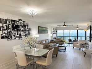 Ein großzügiger Wohnbereich mit Esstisch, Sofas und einem Balkon mit Meerblick.