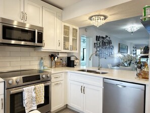A modern kitchen with white cabinetry, stainless steel appliances, and a chandelier. - Sandpiper Key Endless Bay Views & Pool (Englewood)