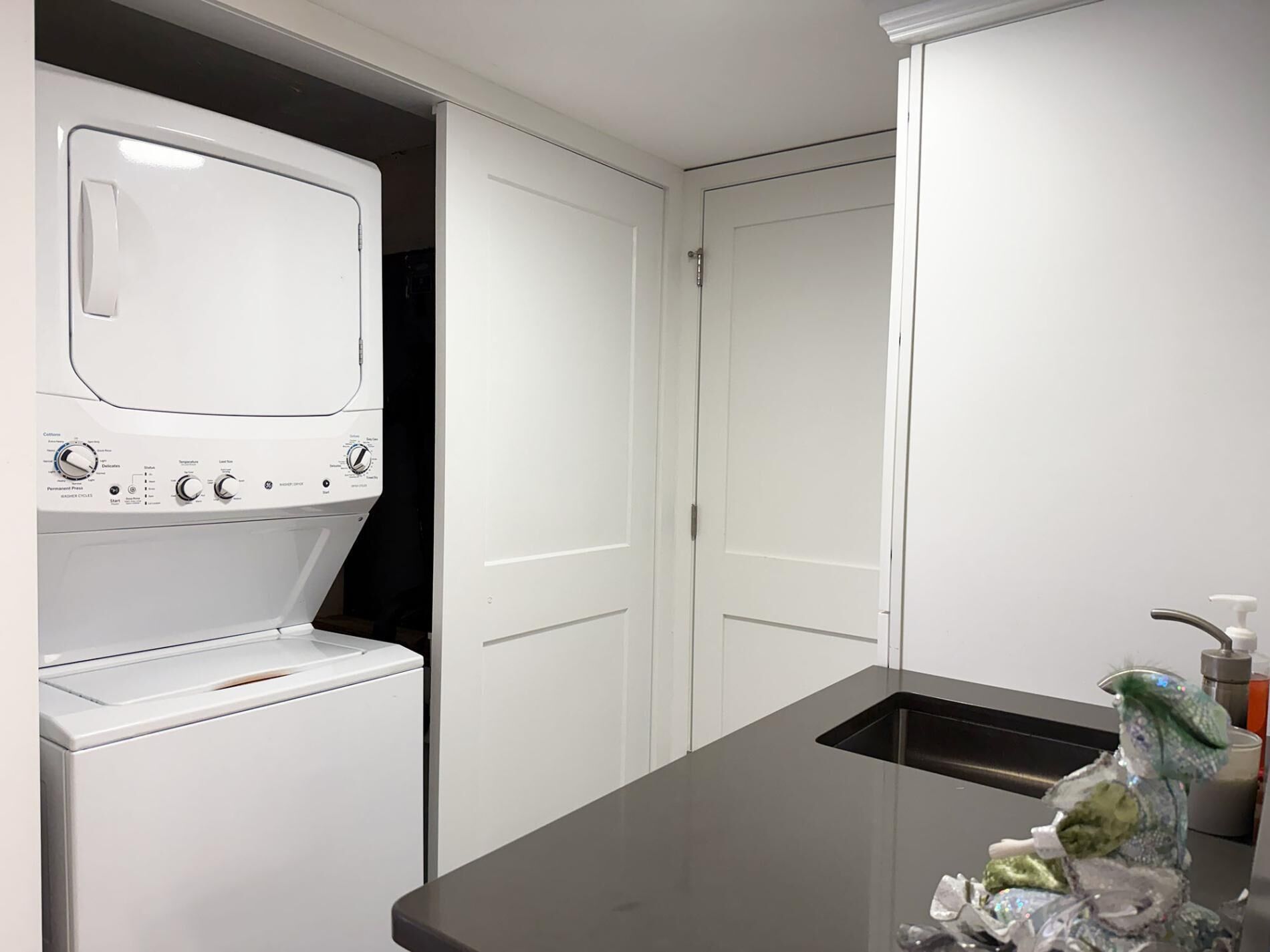 A compact kitchen with a built-in washer and dryer, a sink, and a decorative item on the counter.