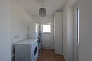 A laundry room with a washing machine, a drying rack, and a window providing natural light. - Grapnells Lodge Wallasea Island Rochford Essex (Rochford)