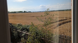 A view of a field through a window, with a wooden fence and some greenery in the foreground. - Grapnells Lodge Wallasea Island Rochford Essex (Rochford)
