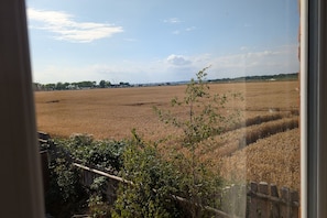 A view of a field through a window, with a wooden fence and some greenery in the foreground. - Grapnells Lodge Wallasea Island Rochford Essex (Rochford)