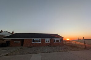 A single-story brick house with a dark roof, a front door, and two windows. - Grapnells Lodge Wallasea Island Rochford Essex (Rochford)