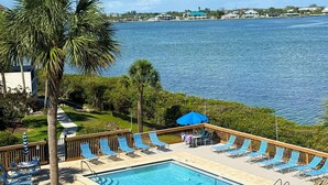 A pool area with lounge chairs and a view of the water. - Sandpiper Key Waterfront Views & Pool (Englewood)