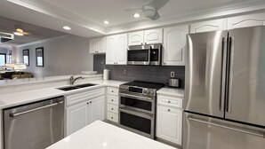 A modern kitchen with white cabinetry, stainless steel appliances, and a marble countertop. - Sandpiper Key Waterfront Views & Pool (Englewood)